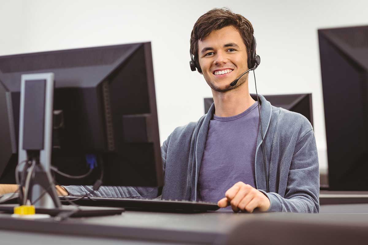 DevOps Schulung - Junger, lächelnder Mann am PC mit Headset