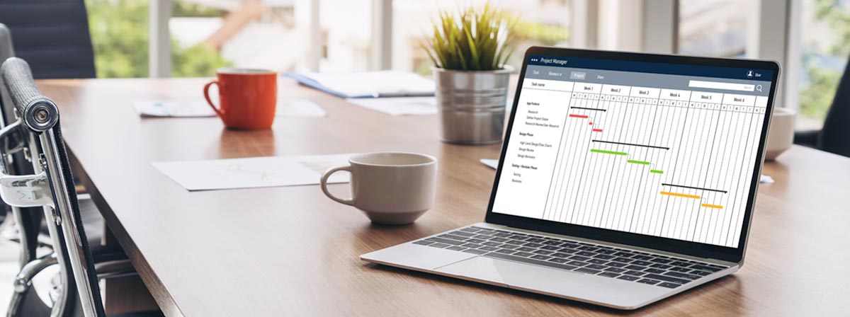 IT Consulting: Laptop mit geöffnetem Projektplan auf dem Schreibtisch